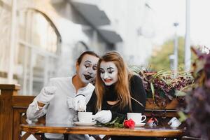 mime vent en meisje in cafe drinken koffie. mime in voorkant van Parijs cafe acteren Leuk vinden drinken thee of koffie. foto