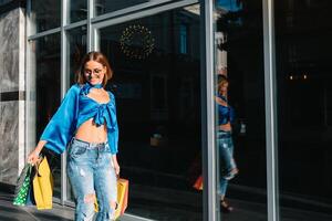 glimlachen jong vrouw poseren met een handvol van boodschappen doen Tassen foto