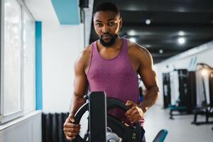 gewicht opleiding Afrikaanse aan het doen bodybuilding in Sportschool. foto