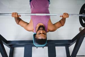 gewicht lifter Bij de bank druk op hijs- een barbell Aan een bank. foto