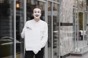 uw tekst hier. acteur mime Holding leeg wit brief. kleurrijk portret met grijs achtergrond. april dwazen dag foto