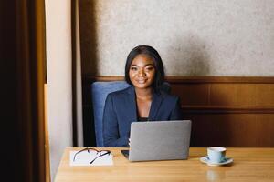 gelukkig jong Afrikaanse Amerikaans zakenvrouw gebruik makend van computer in kantoor foto