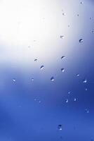 macro fotografie van regendruppels Aan venster met blauw achtergrond foto