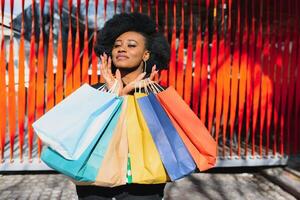 aantrekkelijk jong Afro-Amerikaans vrouw boodschappen doen - boodschappen doen Tassen, buitenshuis, straat visie, geschikt voor vakantie boodschappen doen thema's, tussen anderen foto