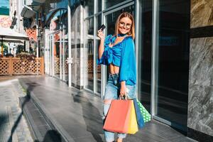 uitverkoop, consumentisme, geld en mensen concept - gelukkig jong vrouw met boodschappen doen Tassen en credit kaart in winkelcentrum foto