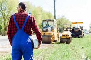 ingenieur bestellingen voor arbeiders naar werk veilig Bij bouw plaats, arbeiders zetten asfalt Aan de weg foto