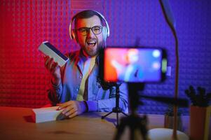 vlogger gebruik makend van smartphone naar film podcast in studio. blogger met mobiel telefoon, microfoon en hoofdtelefoons filmen video voor sociaal media omroep carrière. foto