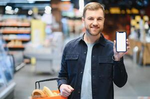 Mens gebruik makend van smartphone in supermarkt. foto