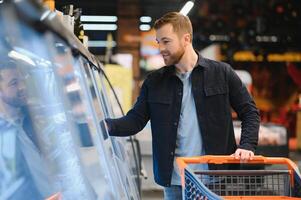 knap Mens buying sommige gezond voedsel en drinken in modern supermarkt of kruidenier op te slaan. levensstijl en consumentisme concept. foto