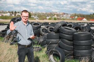 eco-activist Bij de stortplaats van gebruikt auto banden berekent milieu schade. natuur behoud concept foto