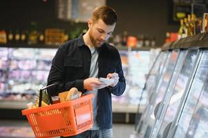 knap Mens buying sommige gezond voedsel en drinken in modern supermarkt of kruidenier op te slaan. levensstijl en consumentisme concept. foto