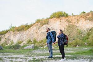 mooi paar van een reizigers zijn zoeken manier Aan plaats kaart terwijl staand Aan hoog heuvel in zonnig dag, mannetje en vrouw wandelaars zijn wandelen samen in bergen gedurende lang in afwachting zomer weekend foto