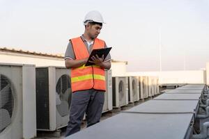 Aziatisch onderhoud ingenieur werken Aan de dak van fabriek. aannemer inspecteren compressor systeem en plannen installatie van lucht staat systemen in bouw. controlelijst, inspecteur, controle foto