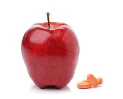 Rode rijpe appel en pillencapsules die op witte achtergrond worden geïsoleerd