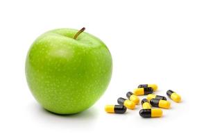 Groene appel en pillencapsules die op witte achtergrond worden geïsoleerd foto