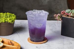 prachtig droom thee of bevroren Purper thee vlinder cocktail geserveerd in beschikbaar glas met ijs kubus geïsoleerd Aan houten bord kant visie van Taiwanees ijs drinken foto