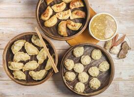 handgemaakt gebakken knoedels met gestoomd knoedel of momo geserveerd in houten schotel met gemengd soep eetstokjes geïsoleerd Aan tafel top visie Japans voedsel foto