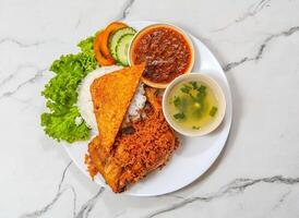 heerlijk Indonesisch voedsel nasi ayam penyet schotel met geroosterd kip deel, rijst, soep, Chili saus en salade geïsoleerd Aan grijs marmeren achtergrond top visie foto