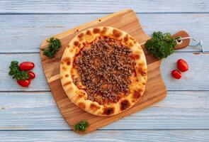 Italiaans gras gevoed rundvlees pizza met tomaten en groente geïsoleerd Aan houten tafel top visie foto