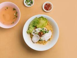 Vietnamees voedsel gesneden vis noodle in een kom met soep, Chili saus en voorjaar ui top visie Aan houten tafel foto