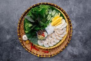 varkensvlees buik met gefermenteerd vis schotel met salade en Chili saus geserveerd in kom geïsoleerd Aan donker grijs achtergrond top visie van Japans voedsel foto