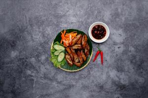 diep gebakken varken darm met vis saus en salade geserveerd in kom geïsoleerd Aan donker grijs achtergrond top visie van Japans voedsel foto