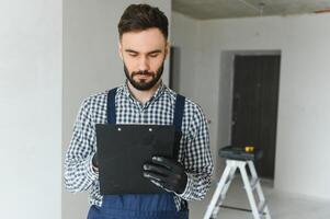 een toegewijd arbeider aan het doen berekeningen voor materiaal voor appartement in bouw werkwijze. foto