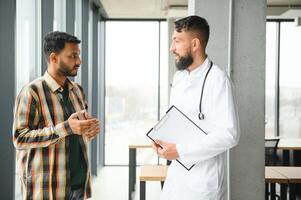 geneesmiddel, gezondheidszorg en mensen concept - gelukkig dokter met klembord en jong mannetje geduldig vergadering Bij ziekenhuis foto