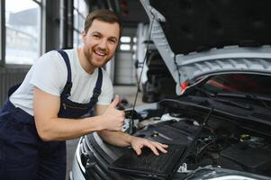 met laptop. volwassen Mens in uniform werken in de auto- salon. foto