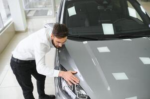 een Mens onderzoekt een auto in een auto handel foto