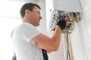 professioneel boiler onderhoud gekwalificeerd technicus controle een natuurlijk gas- boiler Bij huis foto