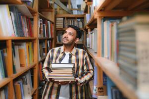 gelukkig slim Indisch of Arabisch jongen, gemengd ras mannelijk, Universiteit leerling, in de bibliotheek foto