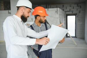 multiraciaal mannetje collega's in harde hoeden bespreken project Aan bouw plaats foto