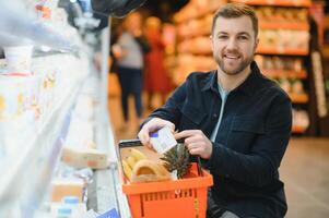 knap Mens buying sommige gezond voedsel en drinken in modern supermarkt of kruidenier op te slaan. levensstijl en consumentisme concept. foto