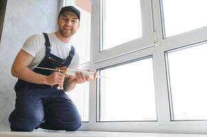 knap jong Mens installeren baai venster in nieuw huis bouw plaats foto