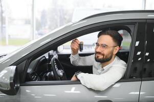 ja, dat is mijn nieuw auto. klant in auto dealerschap. jong Mens met sleutels in hand- foto