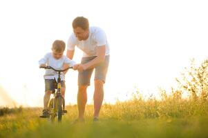 vader helpen zijn zoon rijden een fiets foto
