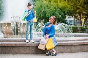 uitverkoop, consumentisme en mensen concept - gelukkig jong Dames haar dauther met boodschappen doen Tassen wandelen stad straat foto