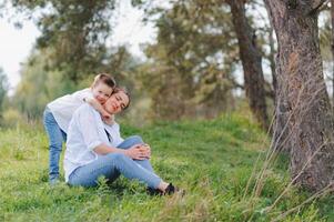 gelukkig jong moeder is spelen met haar baby in een park Aan een groen gazon. geluk en harmonie van familie leven. Super goed familie vakantie. mooi zo weekend. moeders dag. vakantie. de concept van een gelukkig familie foto