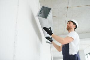 industrieel thema. magazijn verwarming en koeling systeem installatie door professioneel Kaukasisch technicus. reclame gebouw ventilatie rechthoek grachten. lucht verdeling. foto