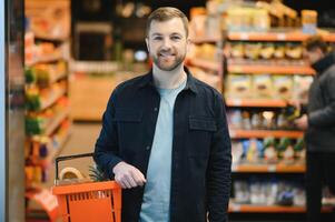 knap jong Mens kiezen voedsel in de supermarkt foto