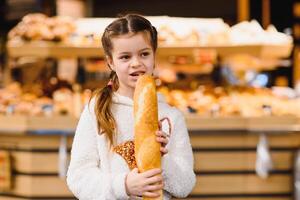 weinig meisje met een baguette in de op te slaan foto