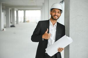 Indisch bouw plaats manager staand vervelend helm, denken Bij bouw plaats. portret van gemengd ras handleiding arbeider of architect. foto