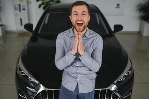 bezoekende auto dealerschap. knap gebaard Mens is strelen zijn nieuw auto en glimlachen foto