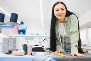 portret van een mooi naaister draag- een plakband meten en werken in een textiel fabriek foto