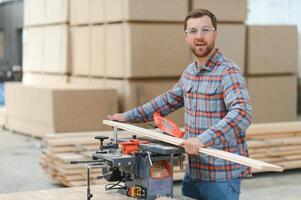 professioneel timmerman gebruik makend van zagen machine voor snijdend houten bord Bij zagerij. foto