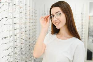 jong vrouw met bril in optisch op te slaan - mooi meisje vervelend bril in opticien winkel foto