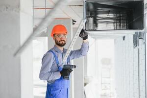 industrieel thema. magazijn verwarming en koeling systeem installatie door professioneel Kaukasisch technicus. reclame gebouw ventilatie rechthoek grachten. lucht verdeling. foto