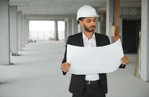 Indisch bouw plaats manager staand vervelend helm, denken Bij bouw plaats. portret van gemengd ras handleiding arbeider of architect. foto