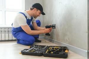 bouw arbeider elektricien assembleert een elektrisch stopcontact in een appartement foto